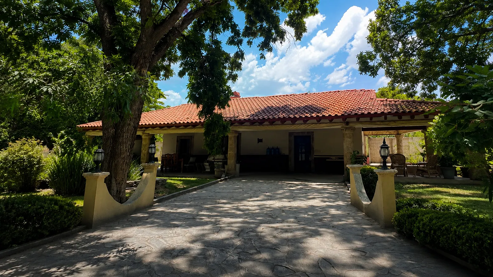 Casa club de Bosquett: techo de teja y pórtico de piedra bajo el arbolado